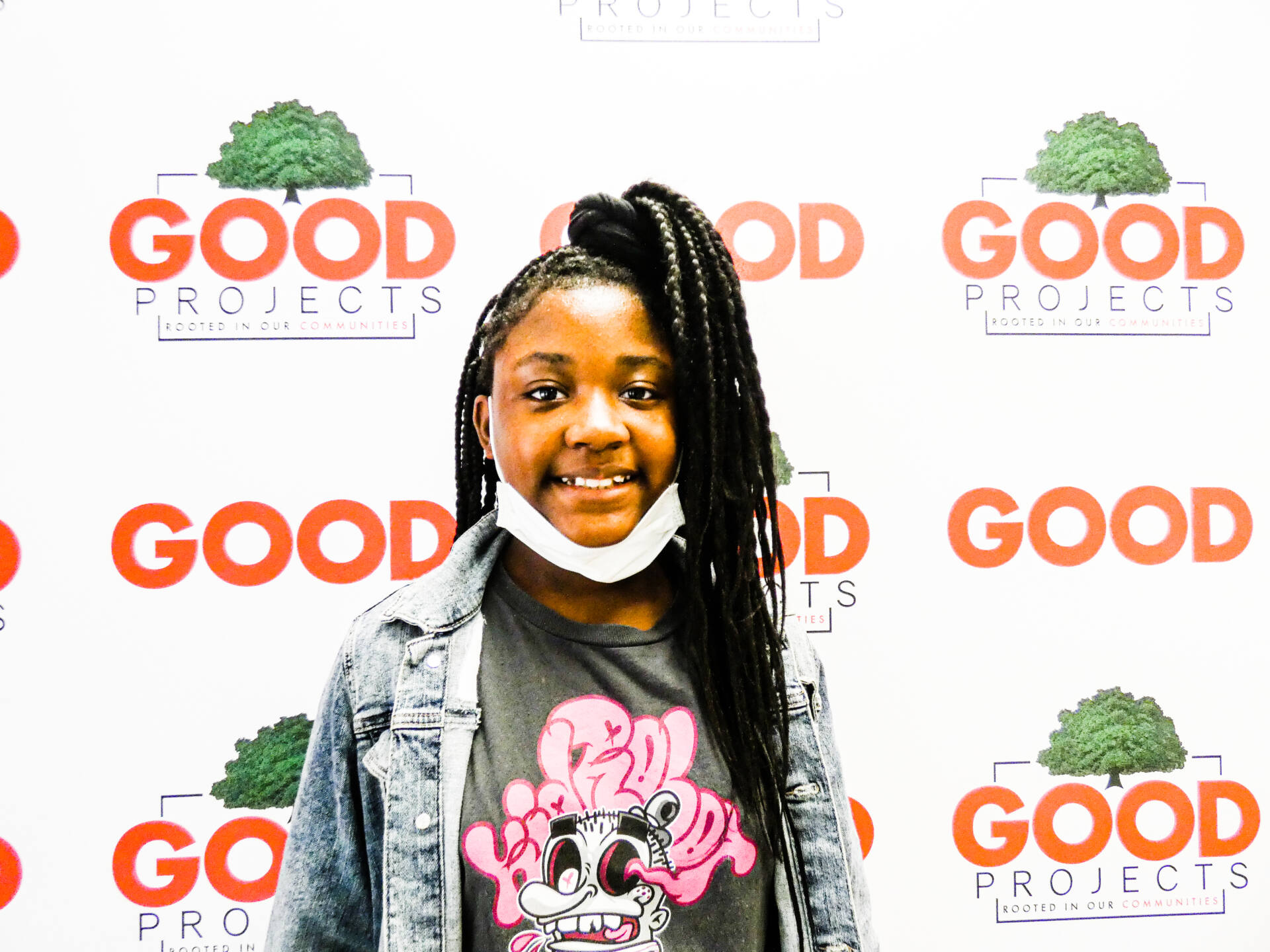 Young girl smiles in front of GOODProjects publicity backdrop