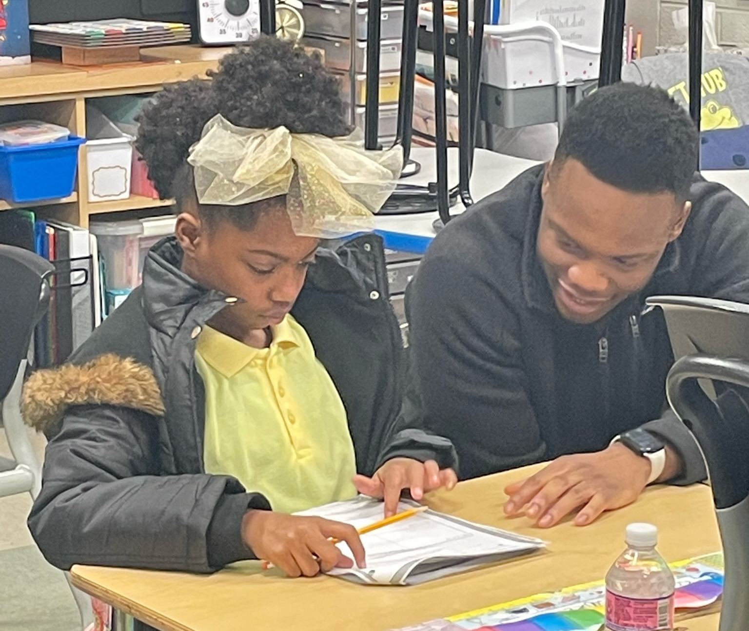 Tutor helps student with reading worksheet at their desk
