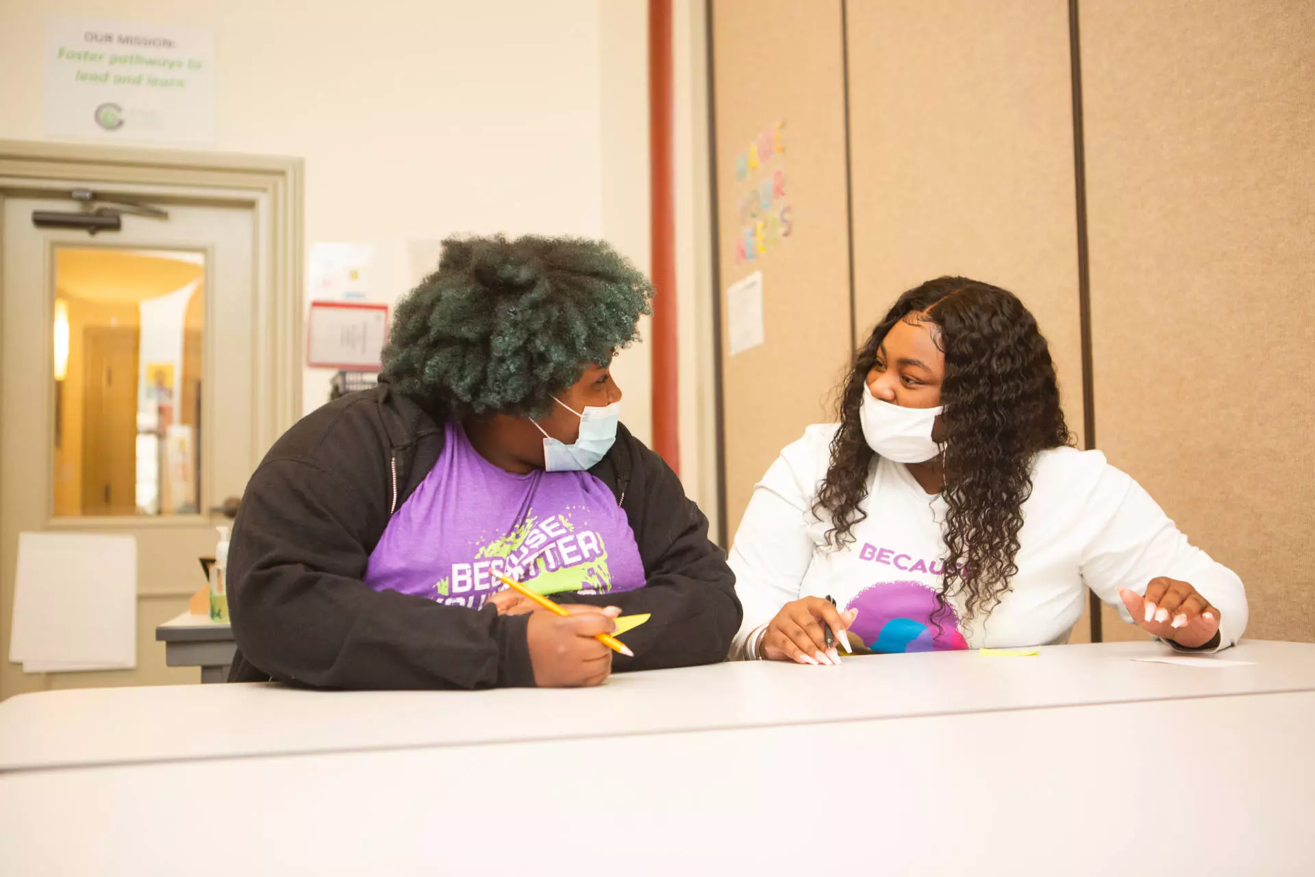 Two volunteers talk with one another while sitting at a tutoring table